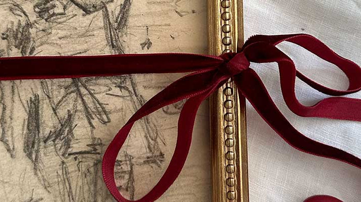 A completed framed vintage print tied with a red ribbon.