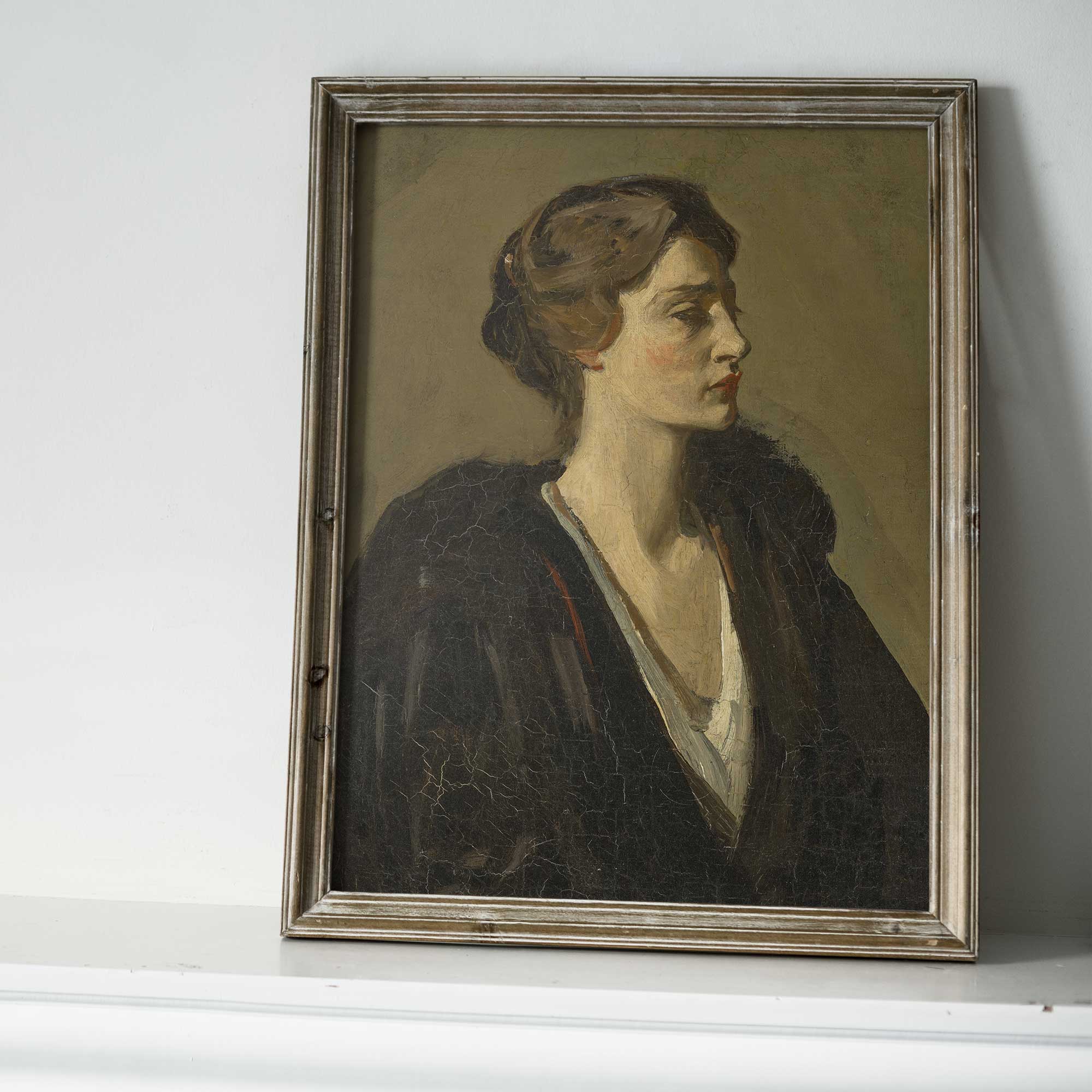 Framed portrait of a woman on a white surface with a gray wall background