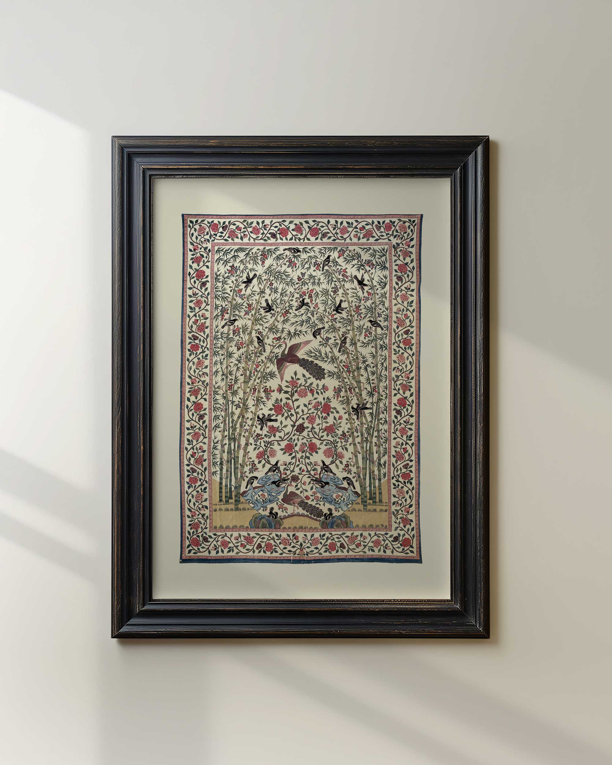 Vintage bird and floral patterned textile print in black frame with natural light.