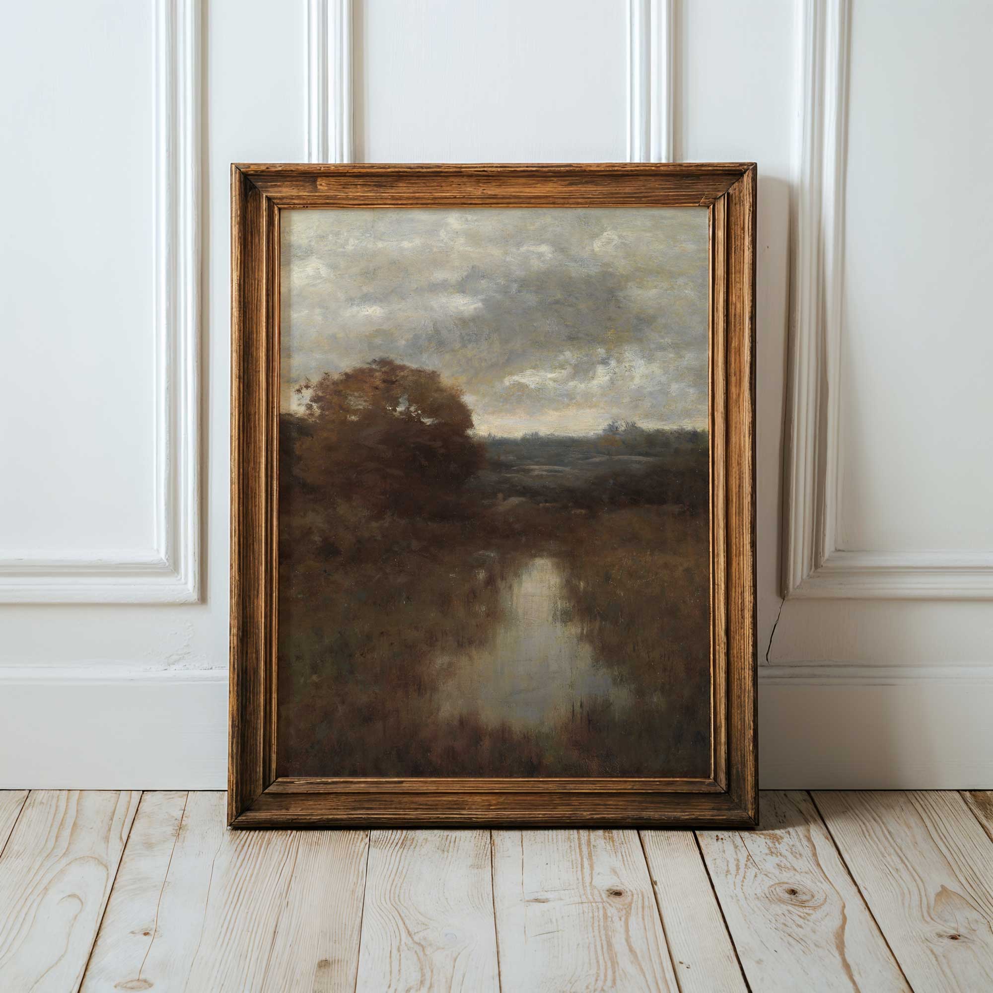 Framed moody landscape painting print on a wooden floor with white panelled walls