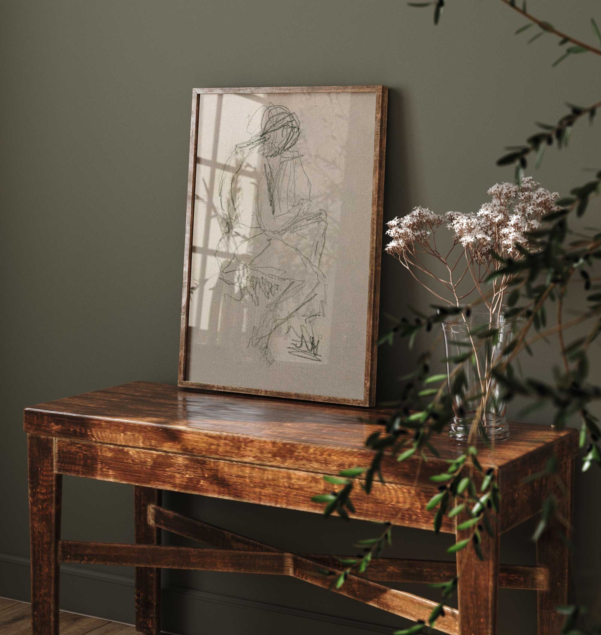 Figure study wall art print — abstract line drawing in neutral tones, framed in brown and leaning against a green wall on a console table