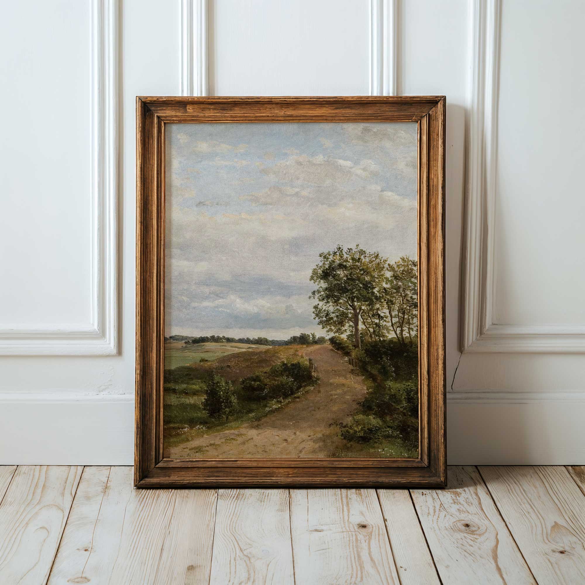 Framed Vintage country landscape print on a wooden floor with white paneled walls