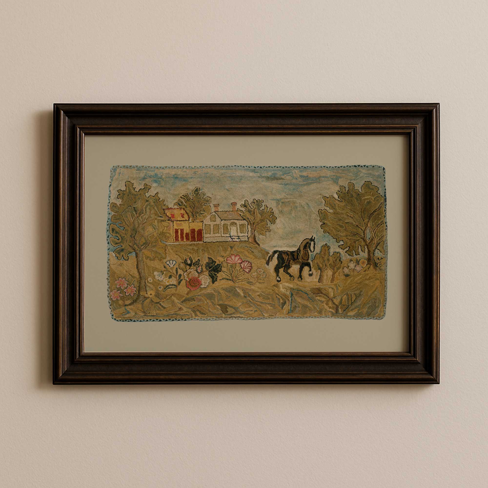 Framed hooked rug nursery print with a pastoral scene of a house, trees, and animals on a beige wall.