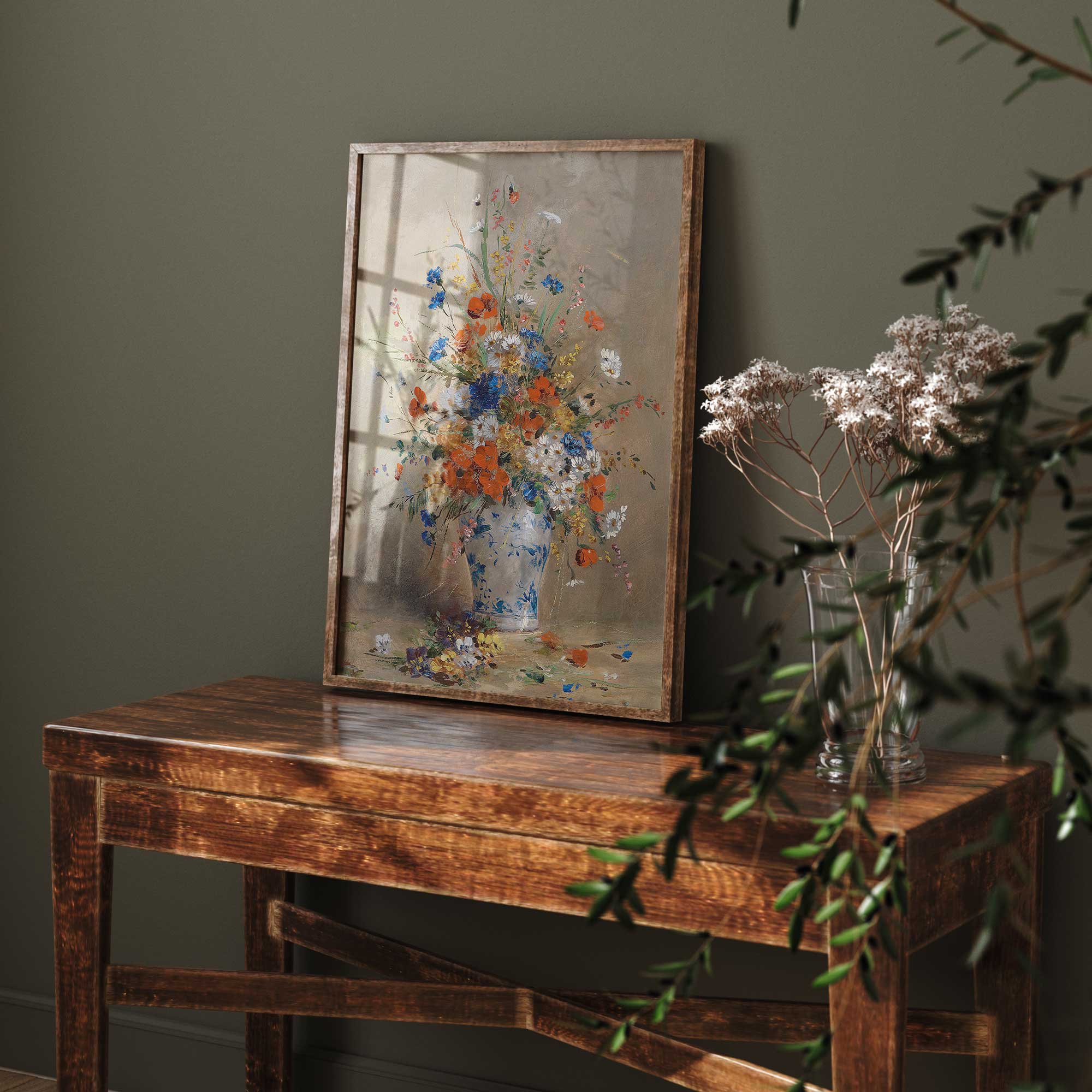 Framed painting of a floral arrangement on a wooden table with a dark green wall background.