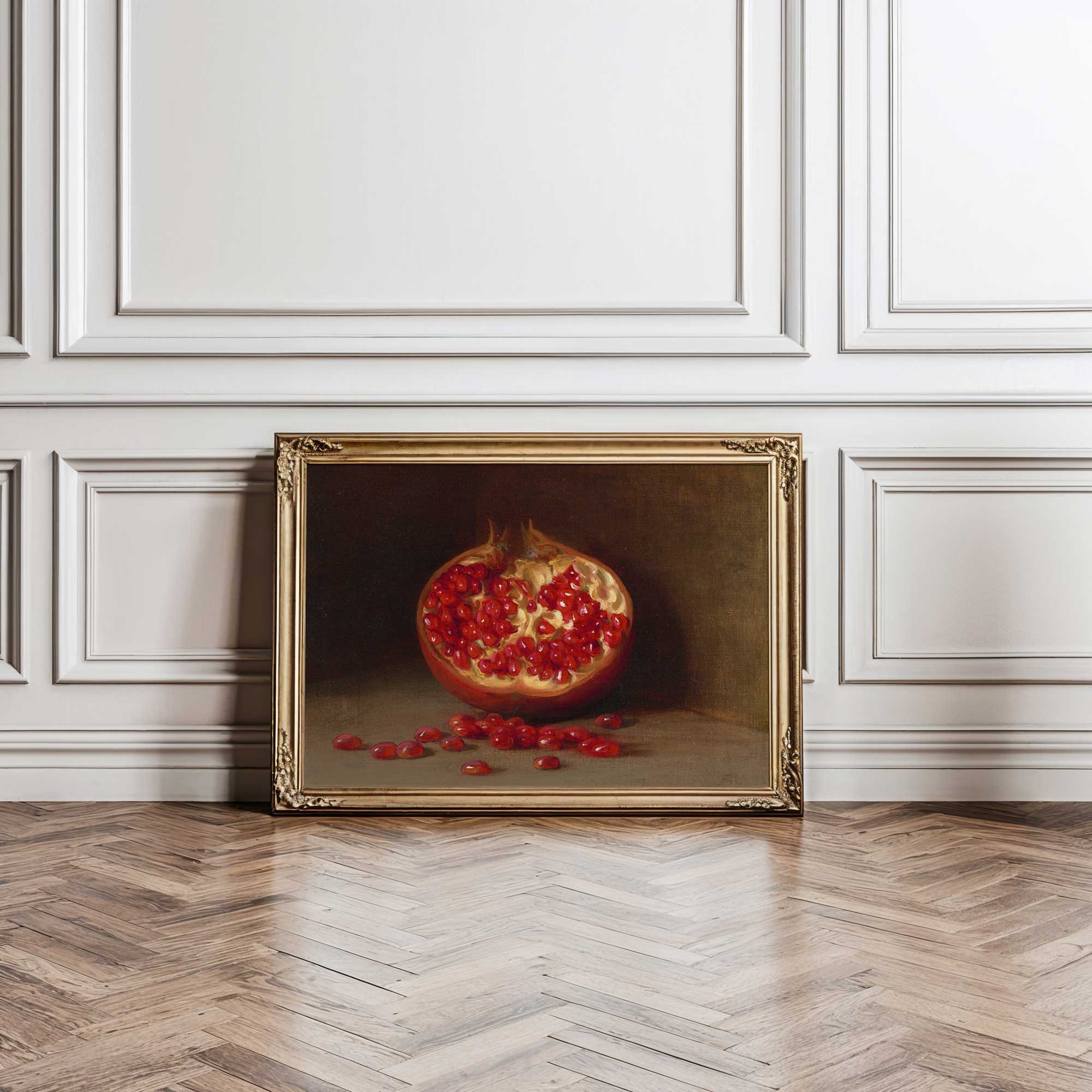 Framed painting of a pomegranate on a wooden floor with white paneled walls.