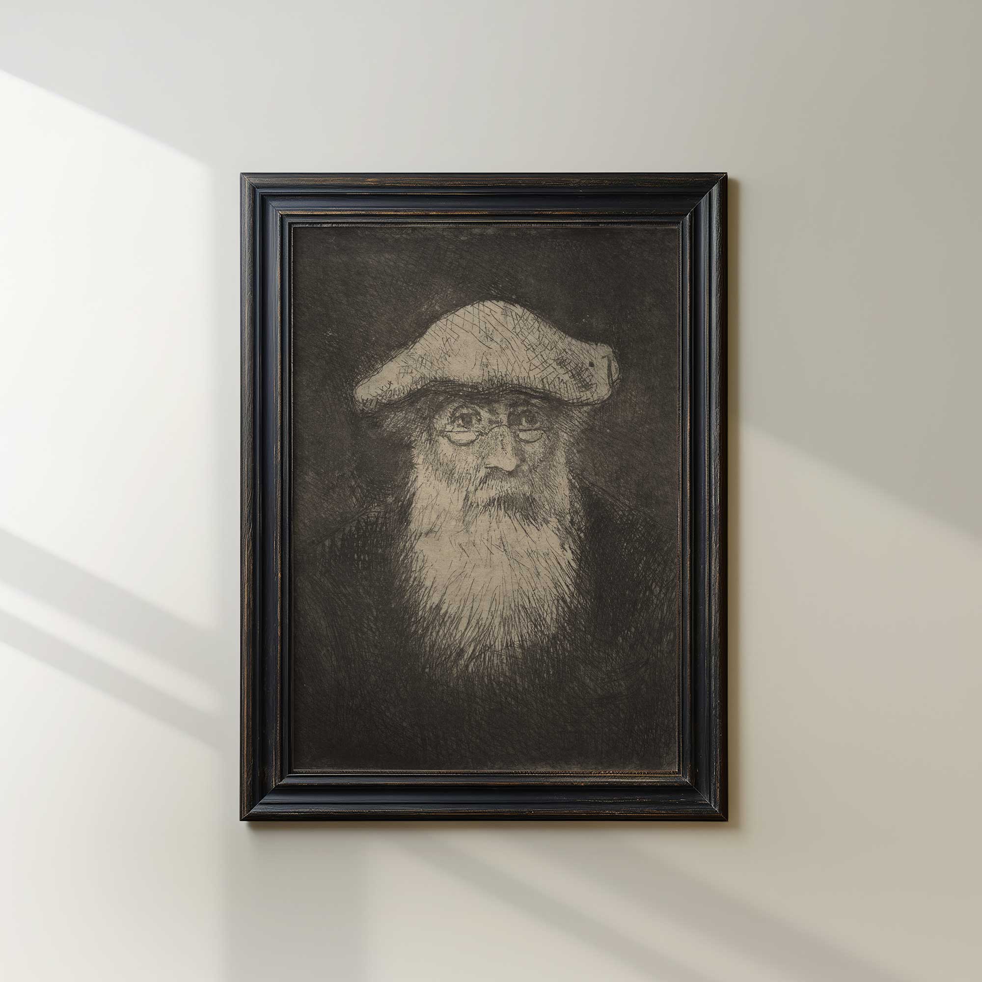 Framed portrait of Camille Pissarro with a beard and hat on a white wall