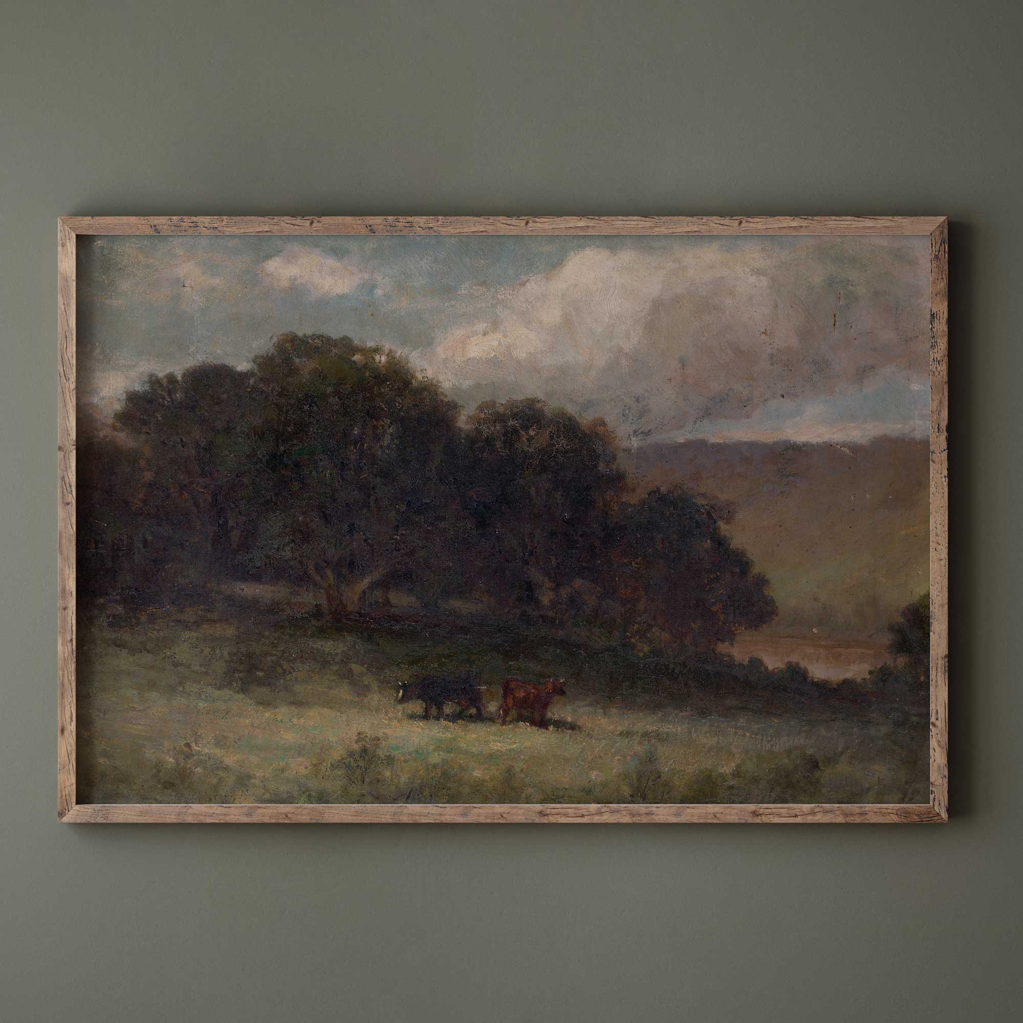 Vintage moody landscape print with grazing cows displayed in a rustic wood frame against a dark green wall