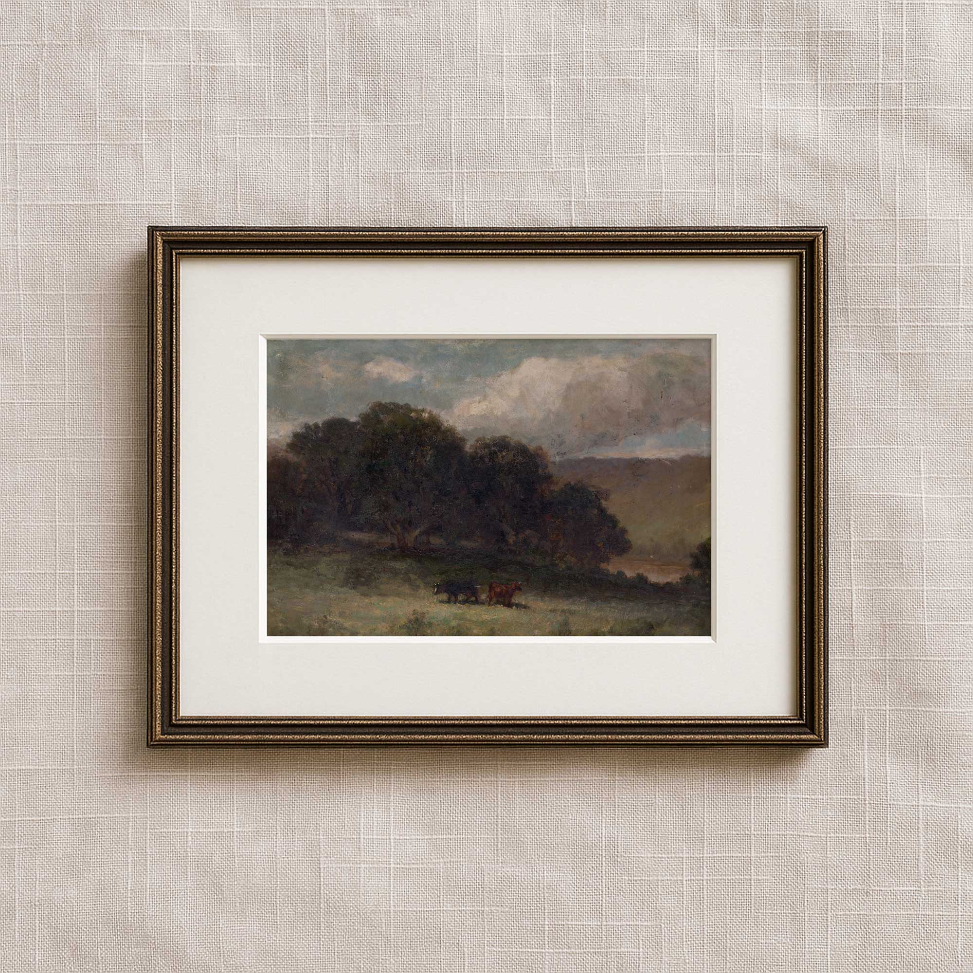 Vintage countryside wall art in matted frame featuring a moody pastoral landscape with cows and woodland trees