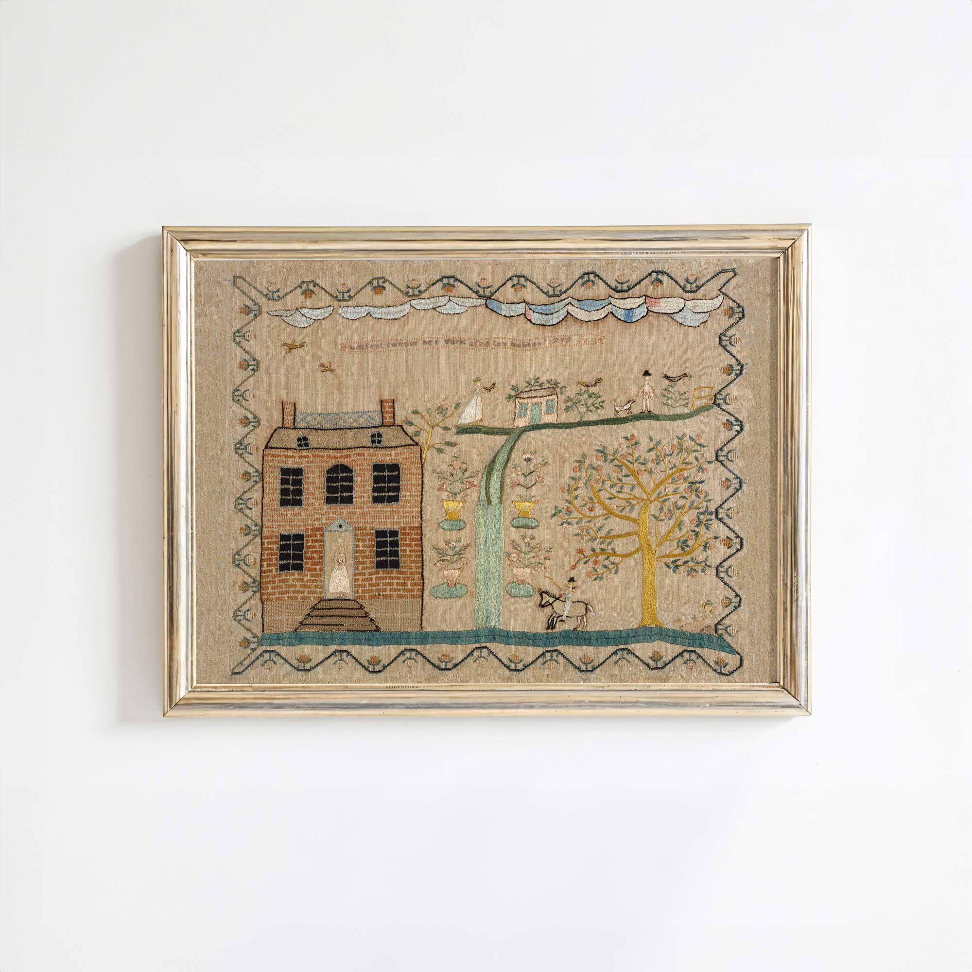 Whimsical folk art house print in light gold frame on a white wall