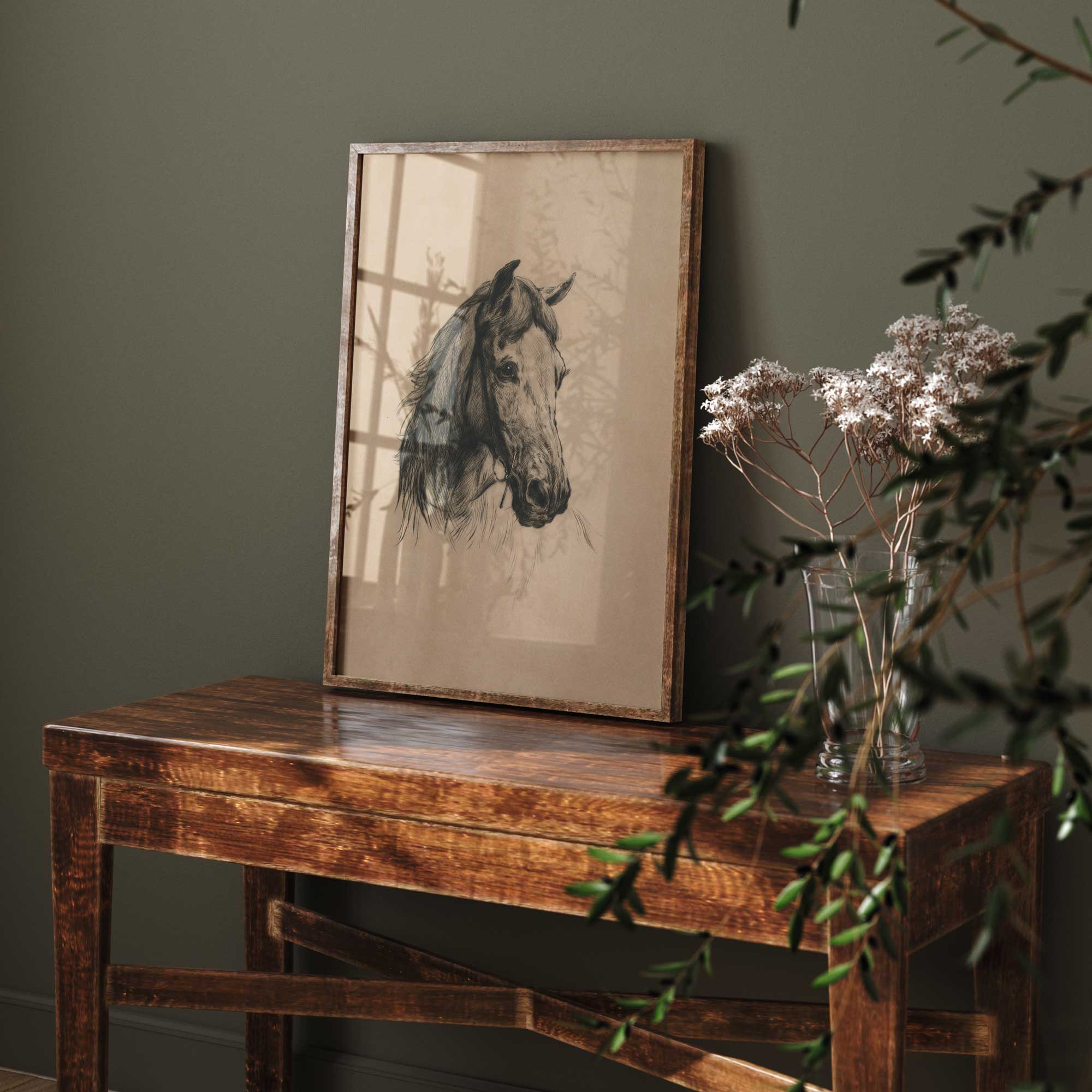 Framed artwork of a horse head on a wooden table against a dark green wall.