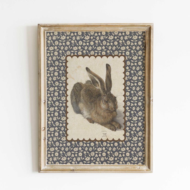 Framed hare print with scalloped border styled on rustic wooden dresser with neutral decor.