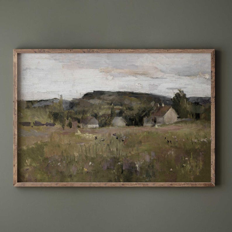 Rustic Nordic countryside landscape art print in gold frame against light wall.