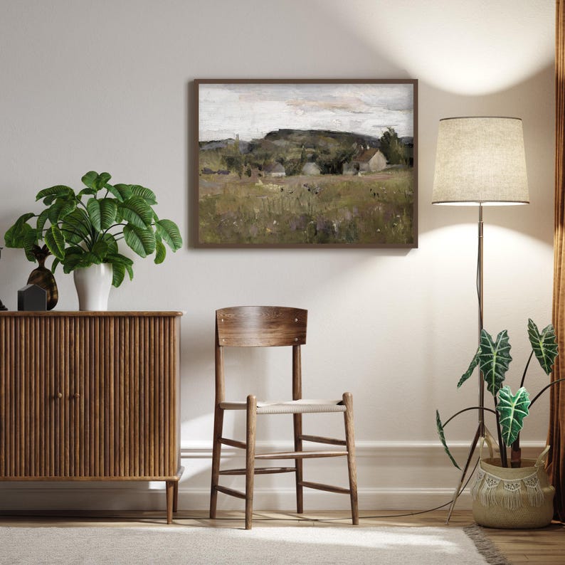 Nordic meadow and cottage wall art leaning on ornate white panelled wall.
