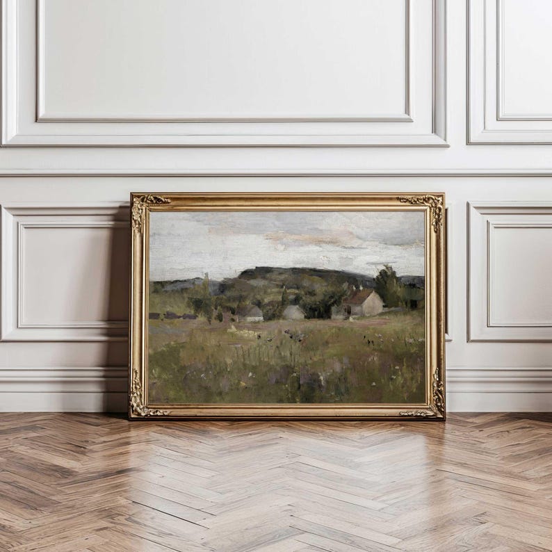 Nordic countryside landscape art print styled above wooden dresser with neutral decor.