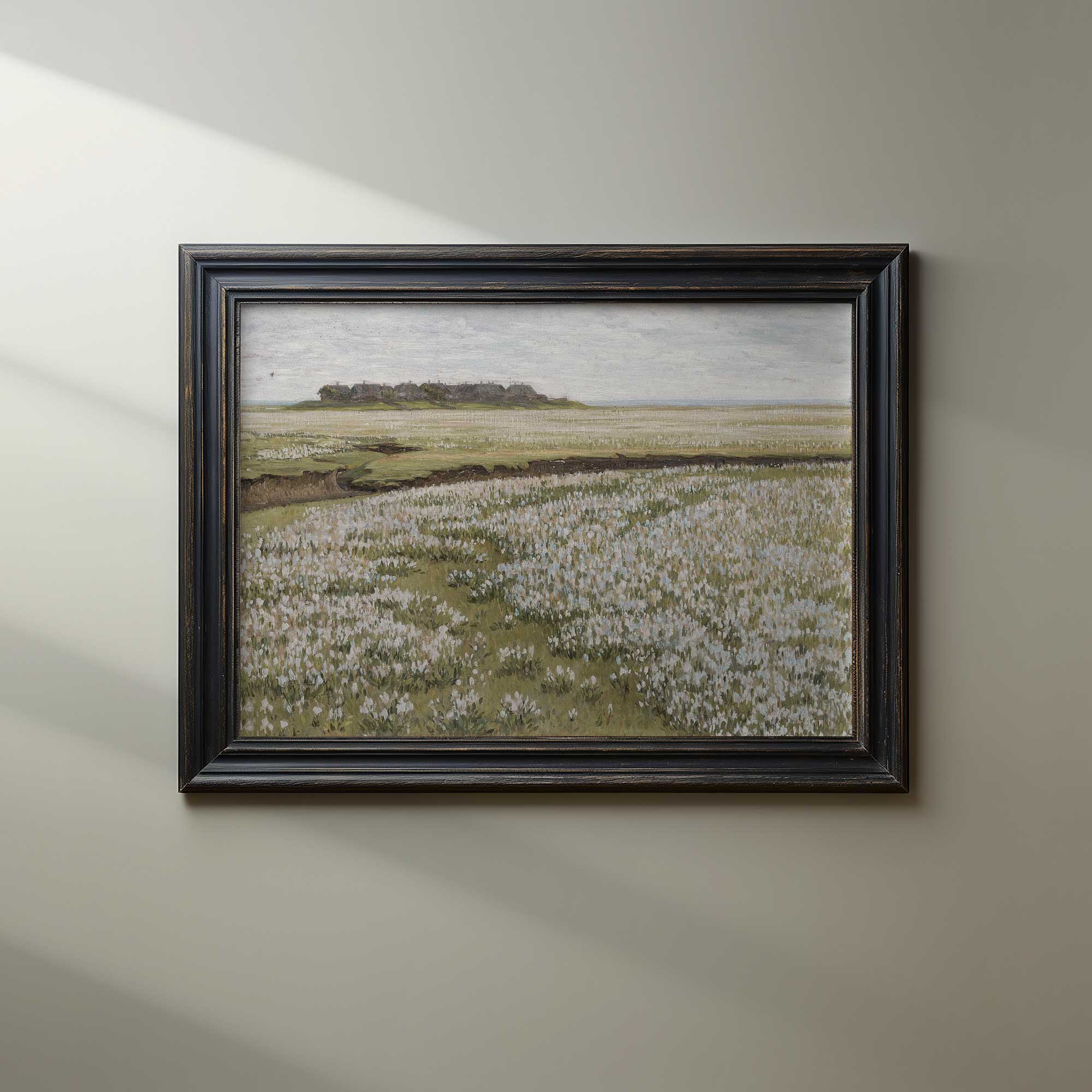 Framed landscape painting of a field with white flowers on a beige wall.