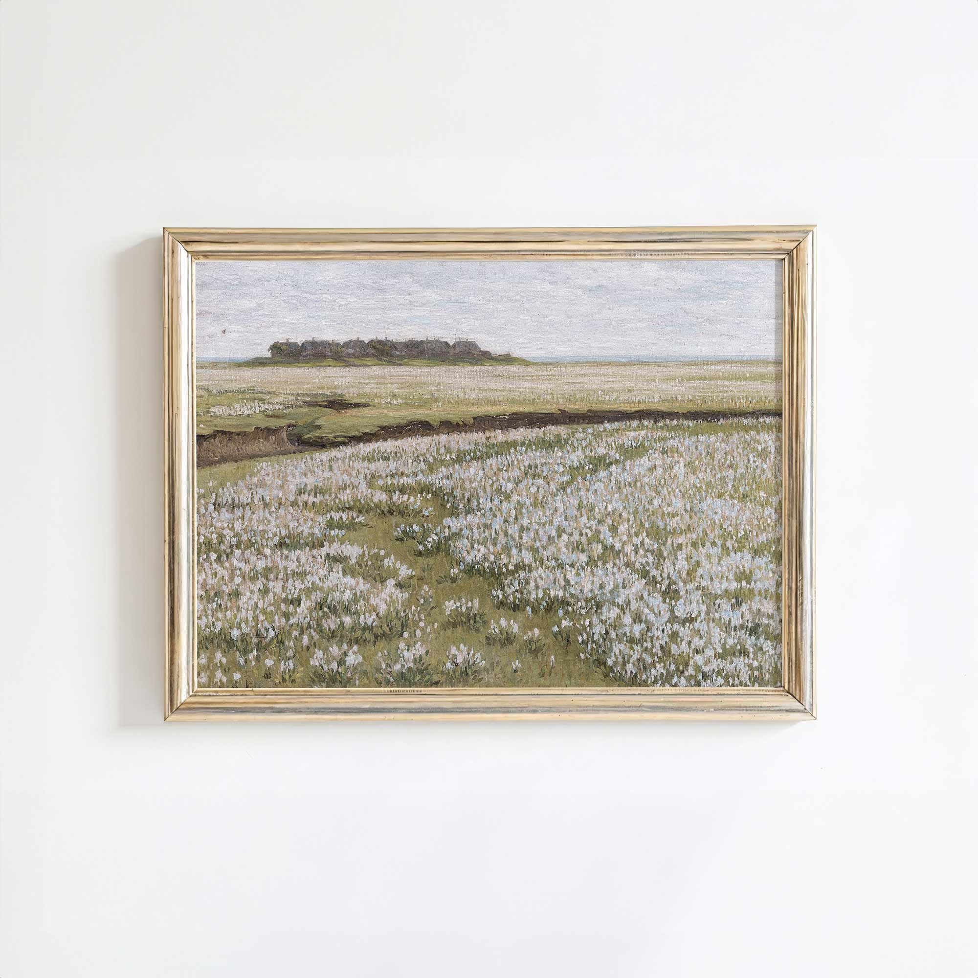 Framed landscape painting of a field with white flowers on a white wall
