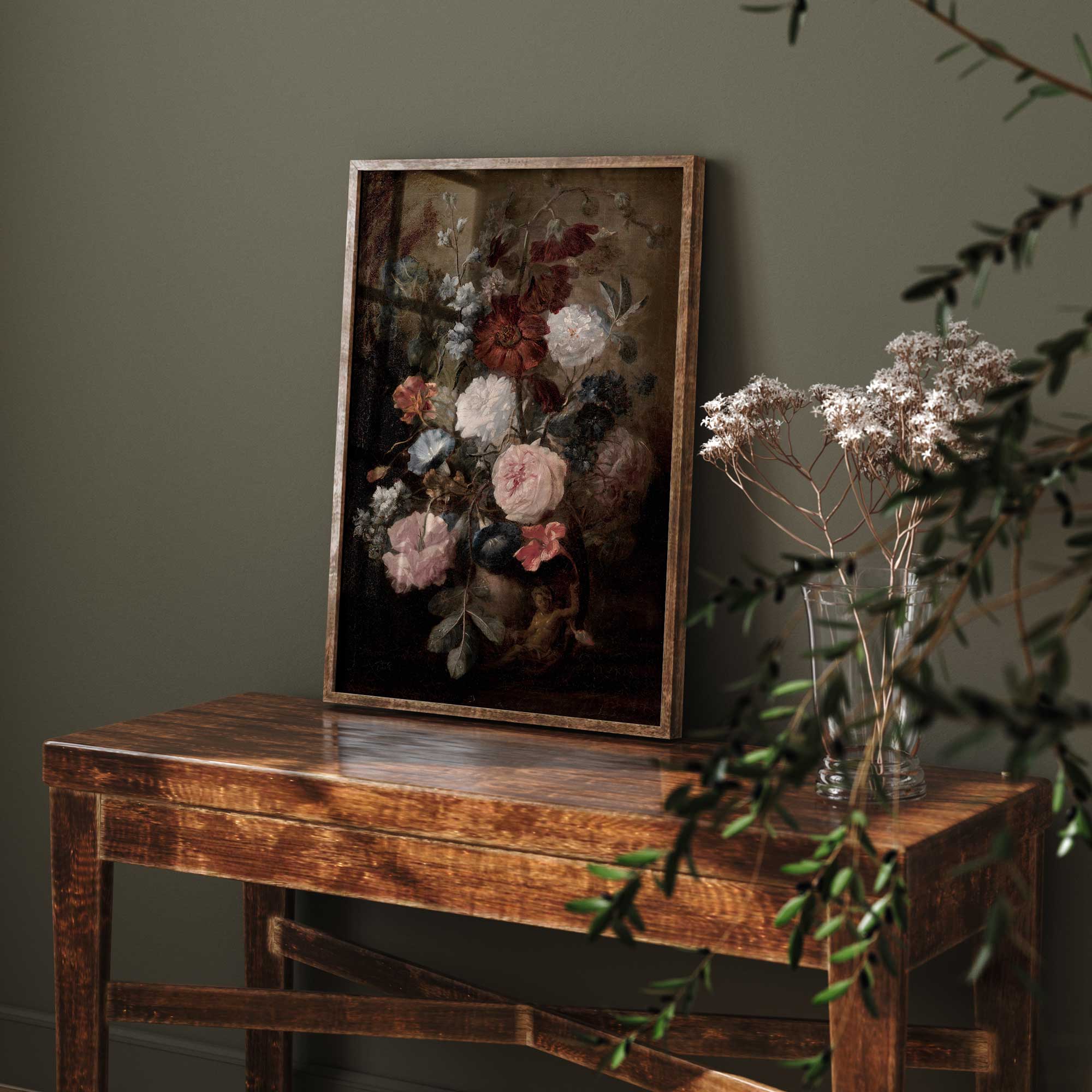 Framed floral painting on a wooden table against a dark green wall