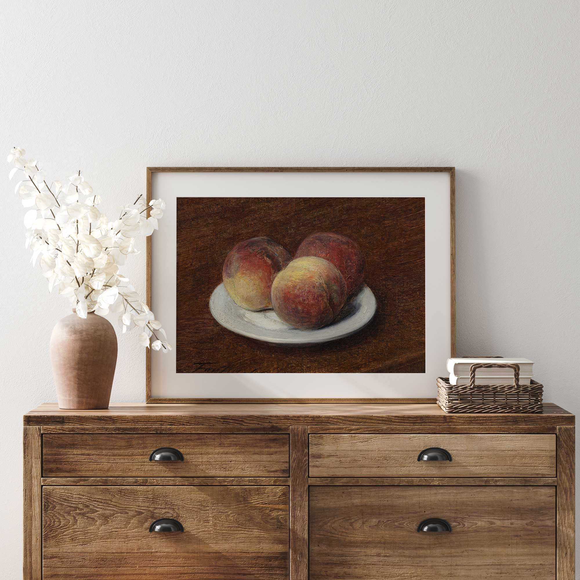 Framed still life painting of peaches on a plate above a wooden sideboard.