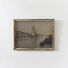 Framed artwork of a sailboat on water with mountains, on a white wall.