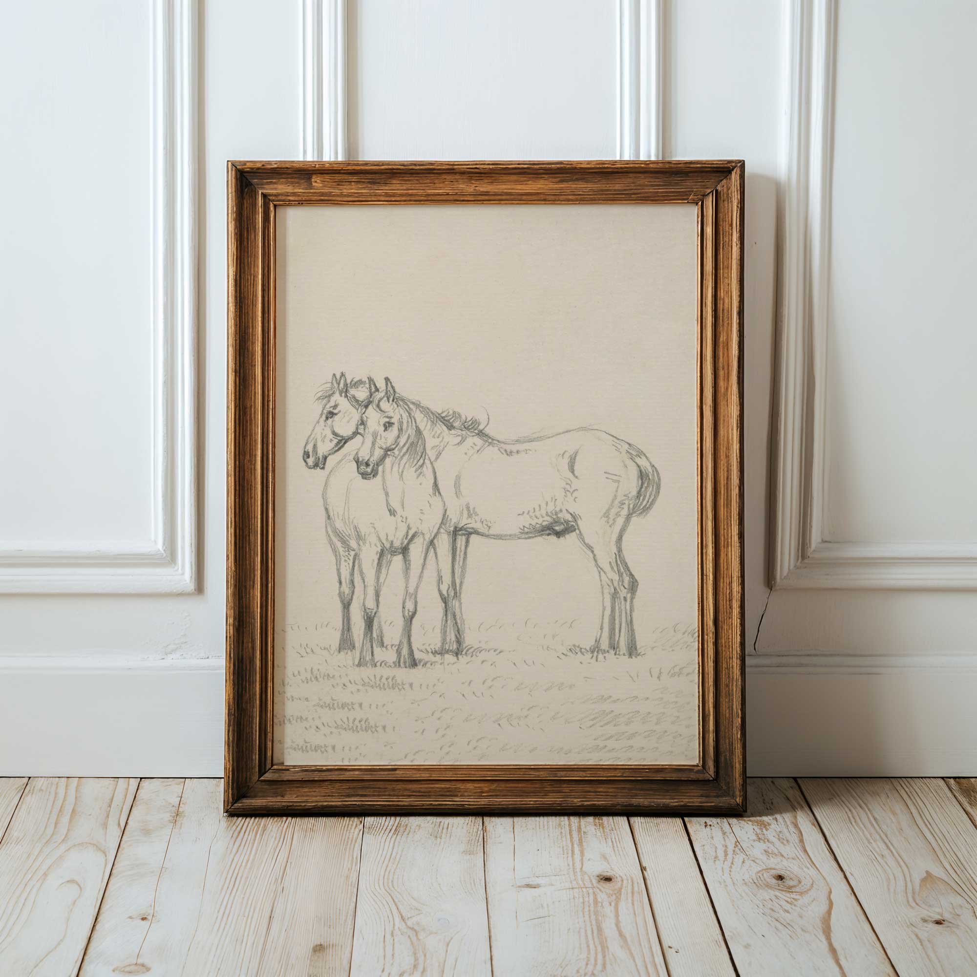 Framed black and white drawing of two horses on a wooden floor with a white paneled wall background.