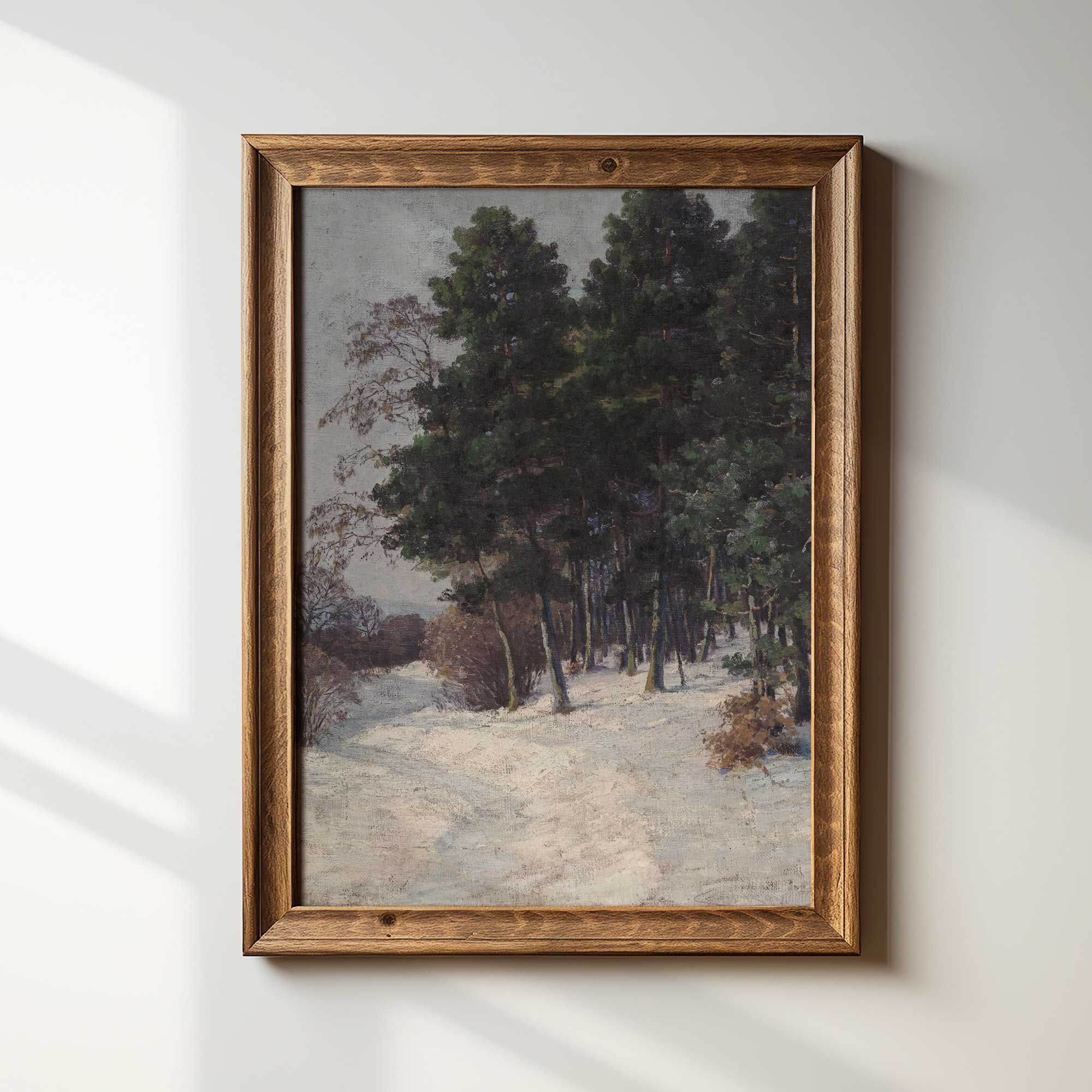 Framed painting of a snowy forest path on a white wall