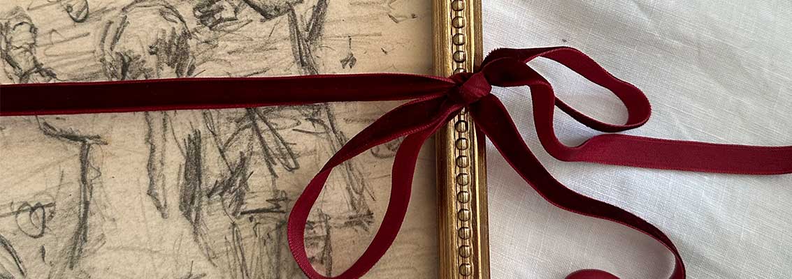 A completed framed vintage print tied with a red ribbon.