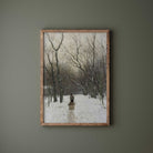 Framed artwork of a snowy landscape with trees and a person on a path, on a green wall.