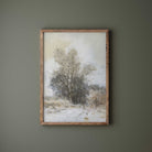 Framed artwork of a winter landscape with trees on a green wall