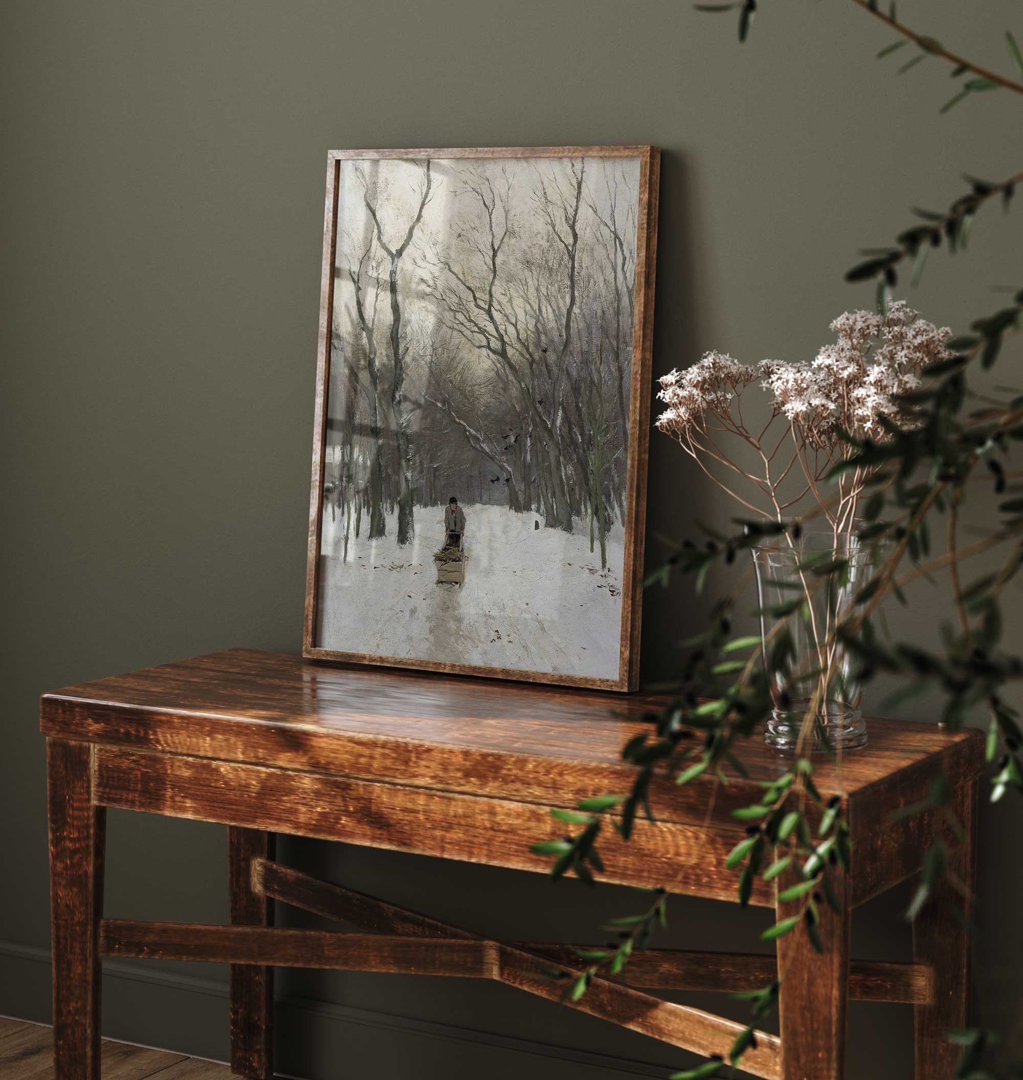 Wooden table with a framed landscape painting against a dark green wall.