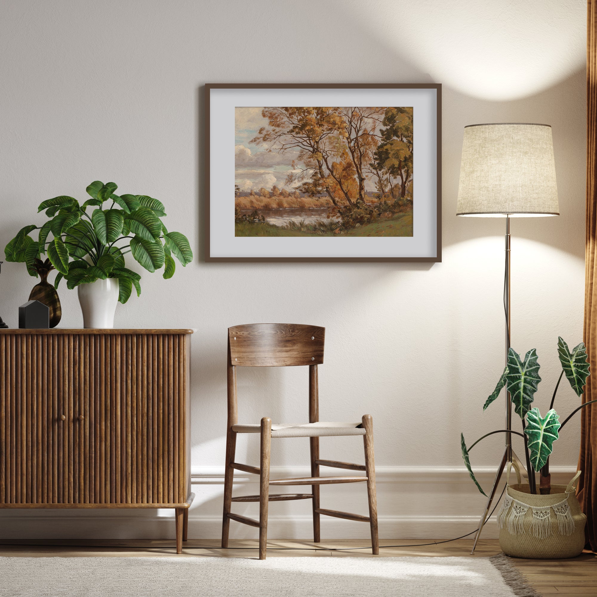 Living room with wooden cabinet, chair, and lamp near a wall with a framed vintage autumn landscape painting.