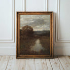 Framed moody landscape painting print on a wooden floor with white panelled walls