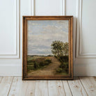 Framed Vintage country landscape print on a wooden floor with white paneled walls