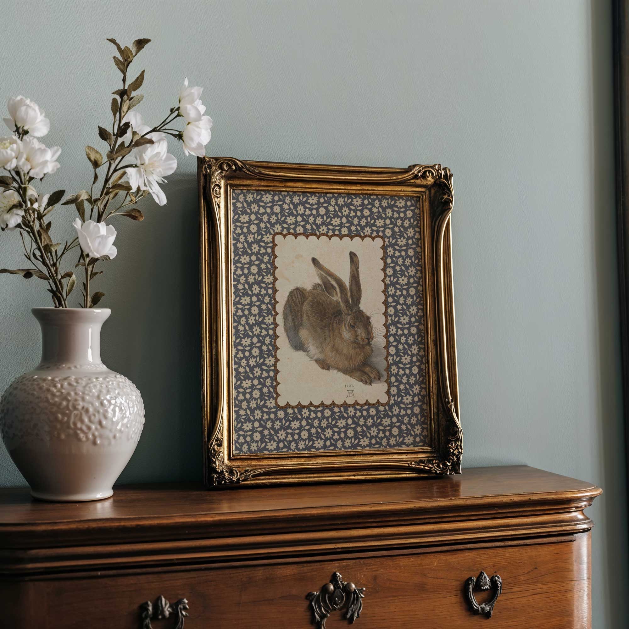 Gold-framed vintage bunny art on a farmhouse-style dresser.