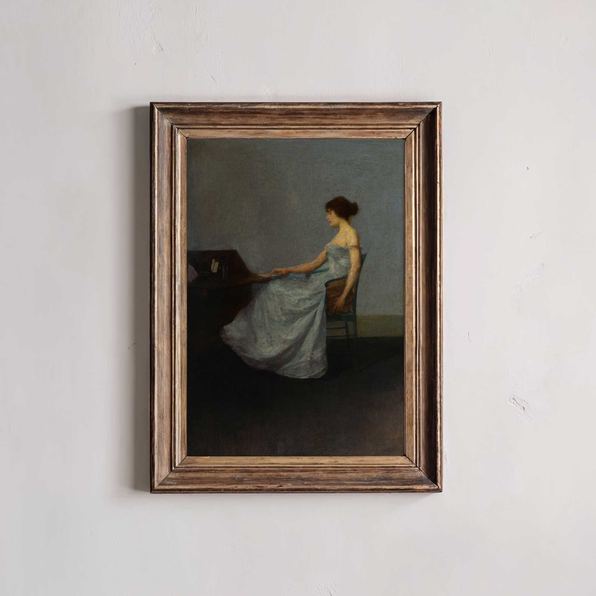 Framed painting of a woman in a blue dress sitting at a piano on a white wall.