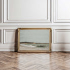 Framed seascape artwork on a wall with decorative paneling and wooden floor.