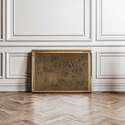 Decorative painting of Hundred horses in rich dark tones in a gold frame on a wooden floor with white panelled walls.