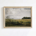 Framed Rustic landscape oil painting print of a field with trees and clouds on a white wall