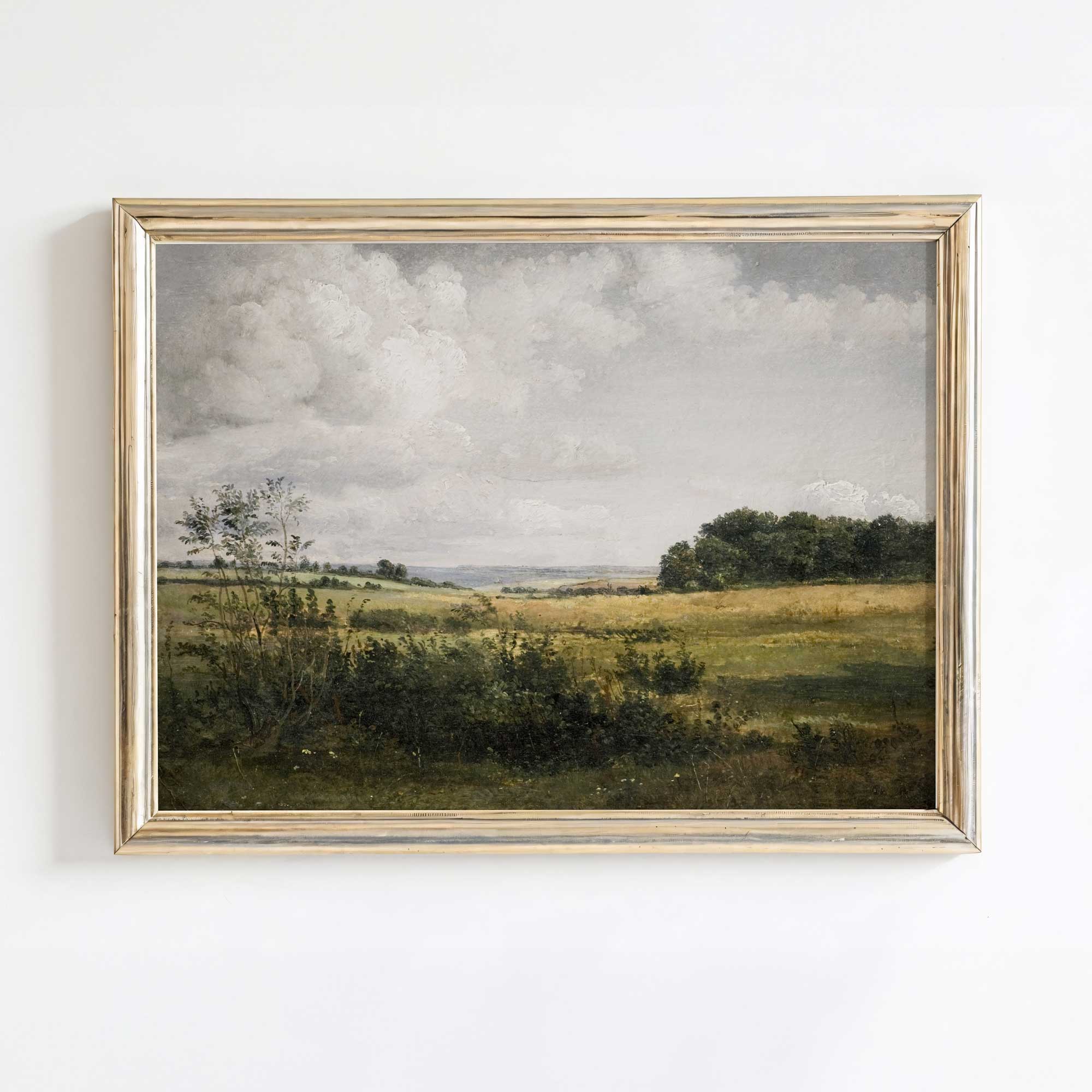 Framed Rustic landscape oil painting print of a field with trees and clouds on a white wall