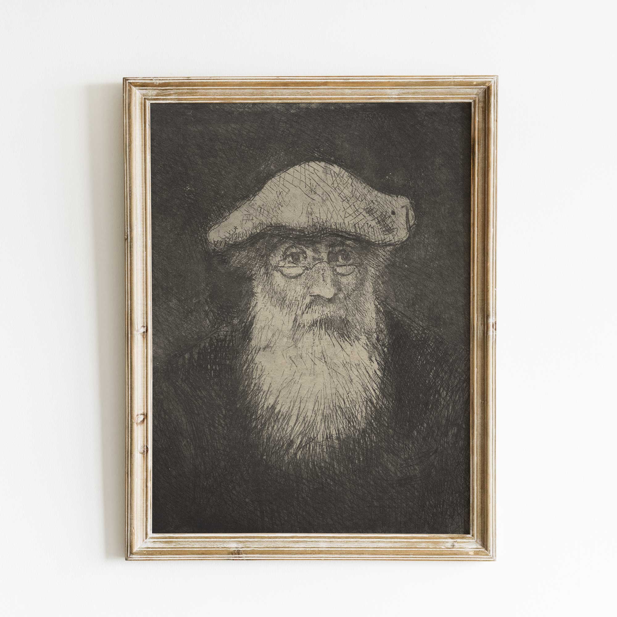 Framed black and white portrait Camille Pissarro on a white wall.