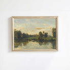 Framed landscape painting of a river and trees on a white wall