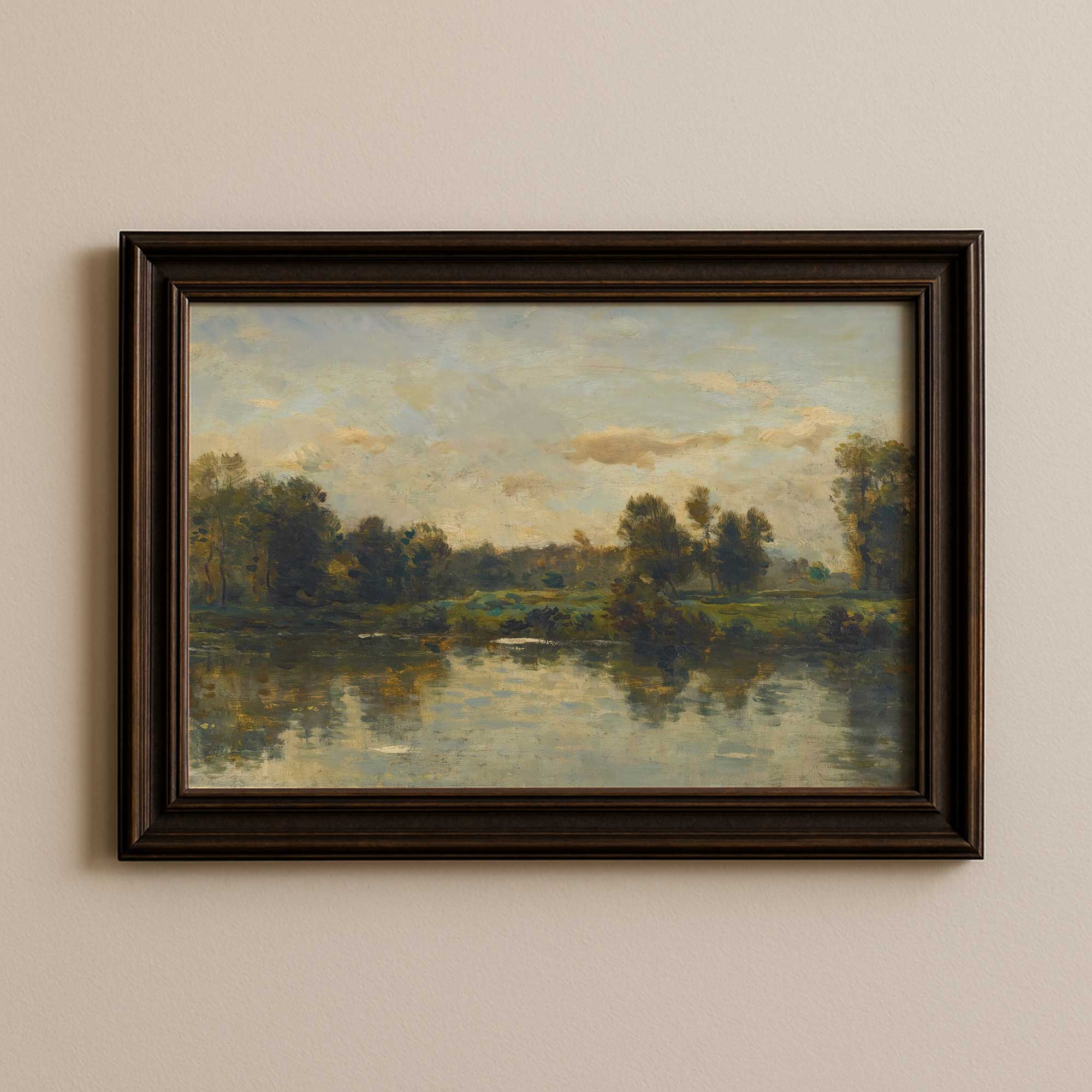 Framed painting of a landscape with a river and trees on a beige wall.