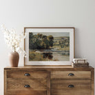 Vintage summer landscape print displayed above a rustic dresser in a farmhouse interior.
