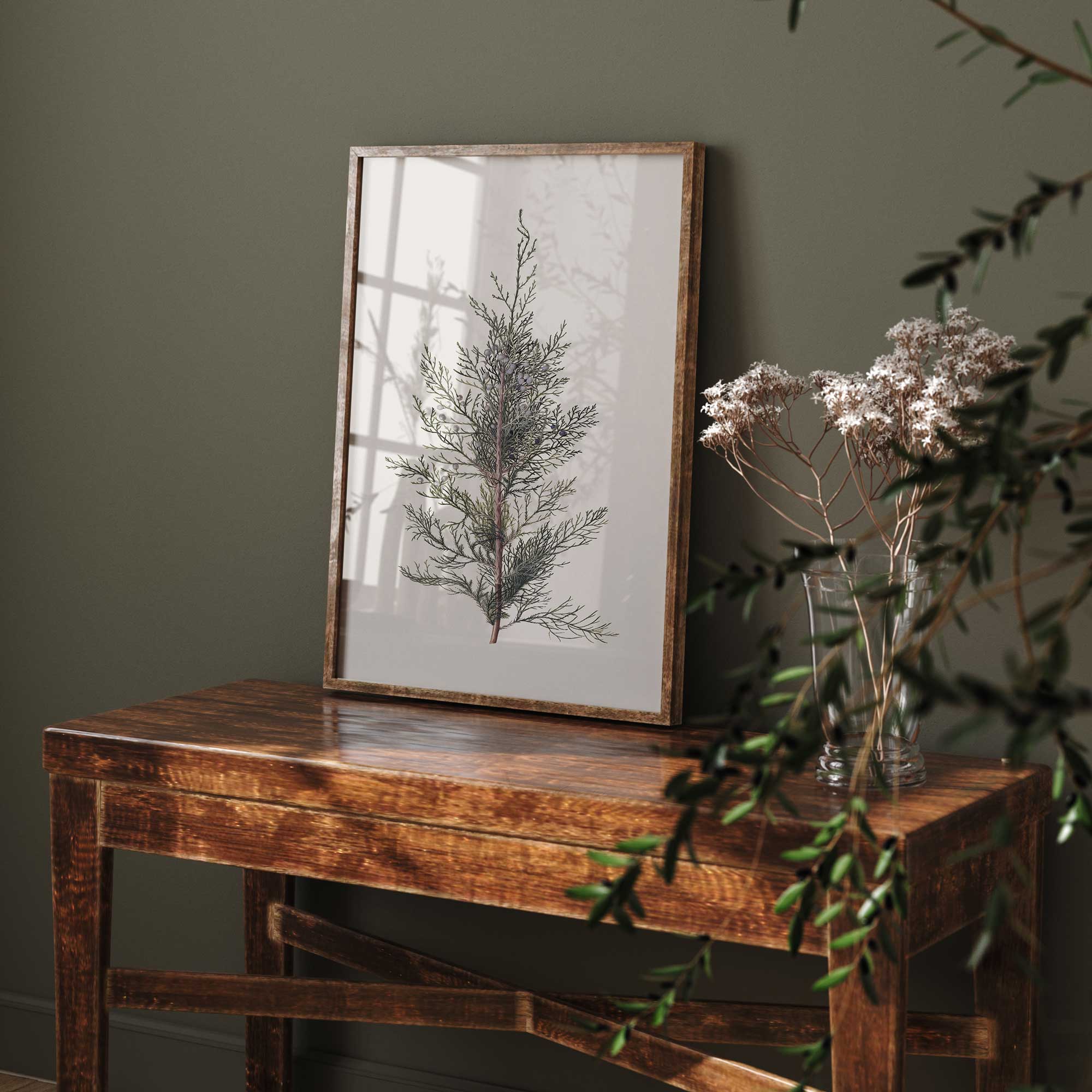 Framed botanical print on a wooden table with greenery in the background