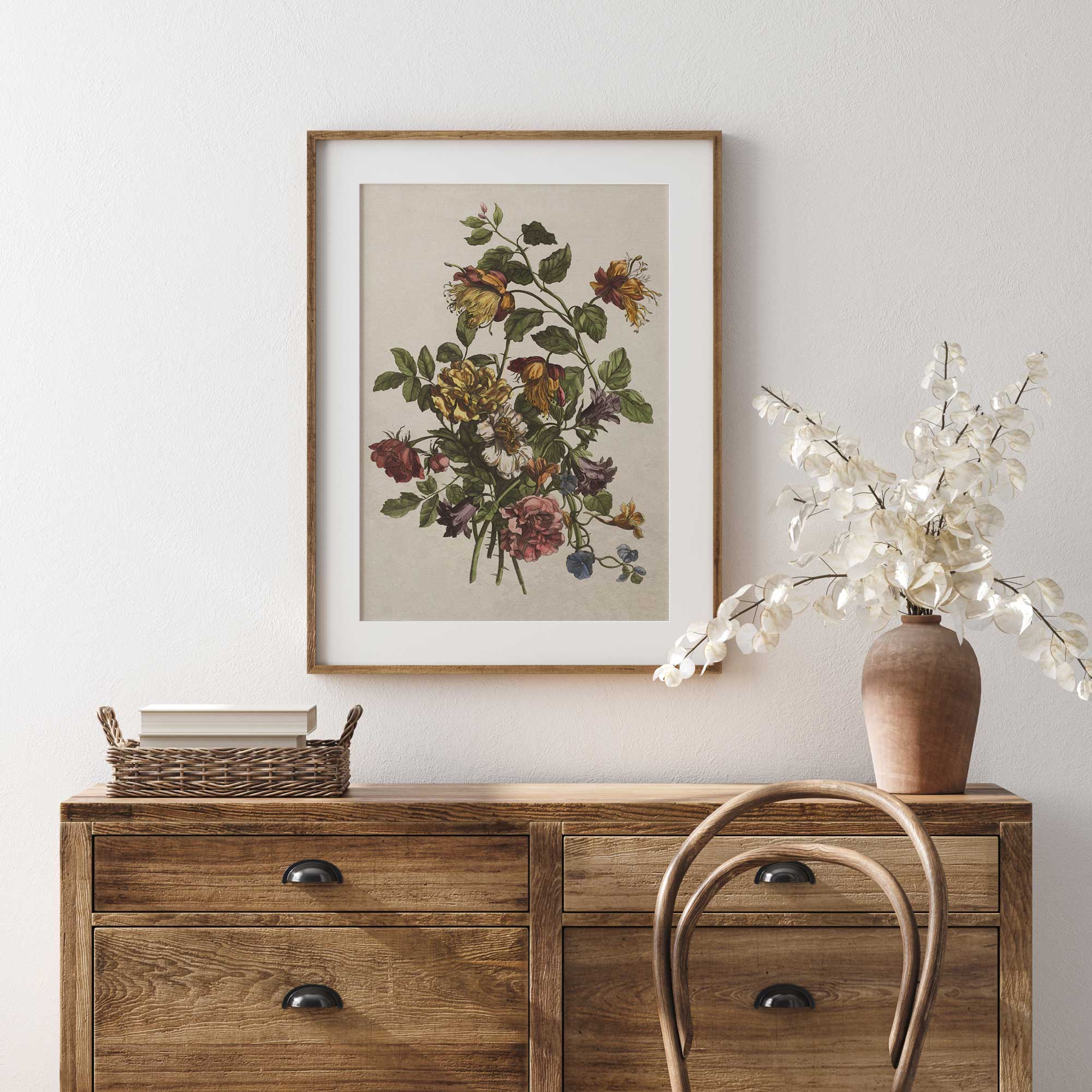 Wooden dresser with a framed floral print and decorative items against a light wall.