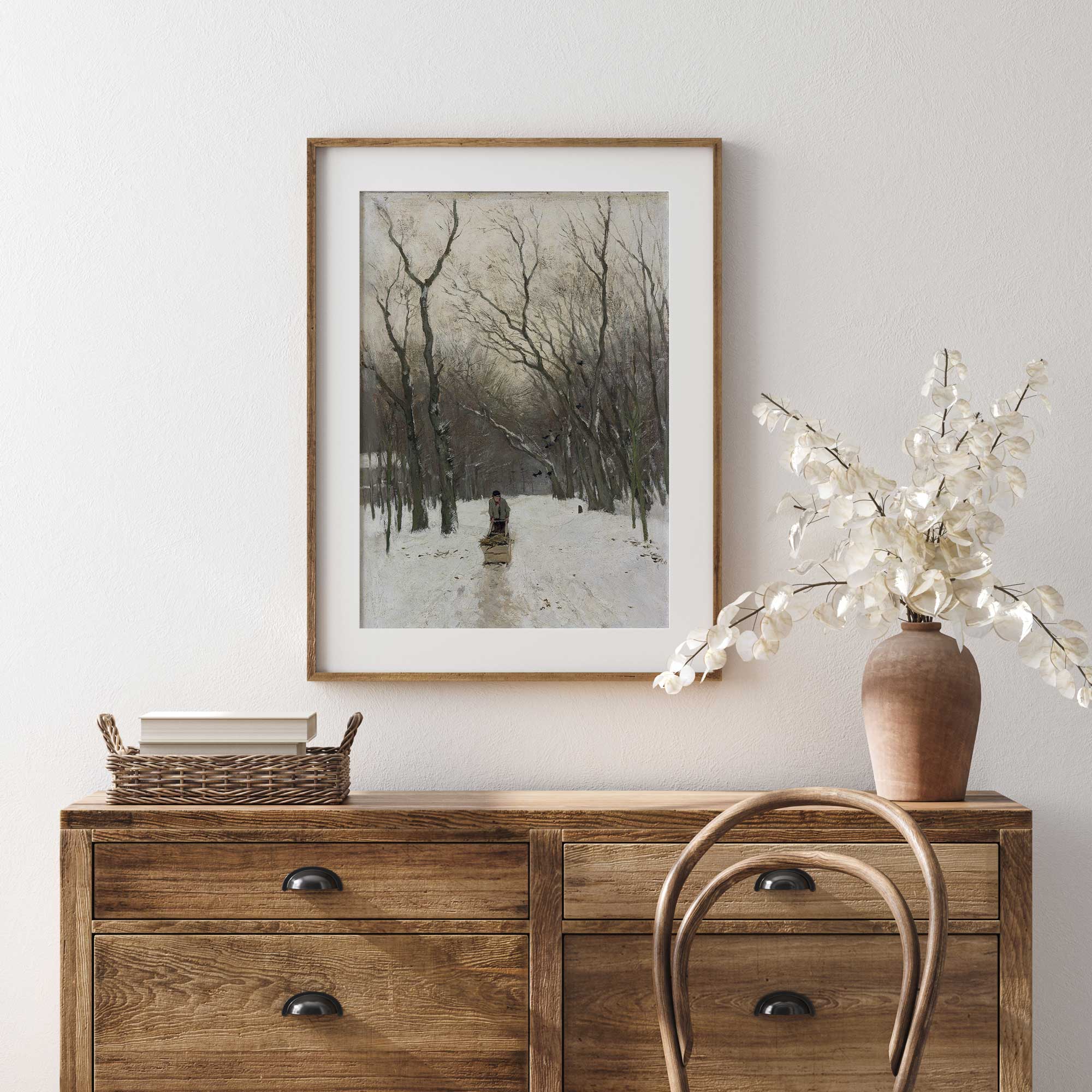 Wooden dresser with a framed landscape print and decorative items on a light gray wall.