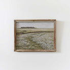 Framed artwork of a landscape with Blooming Floral Meadow on a white wall.