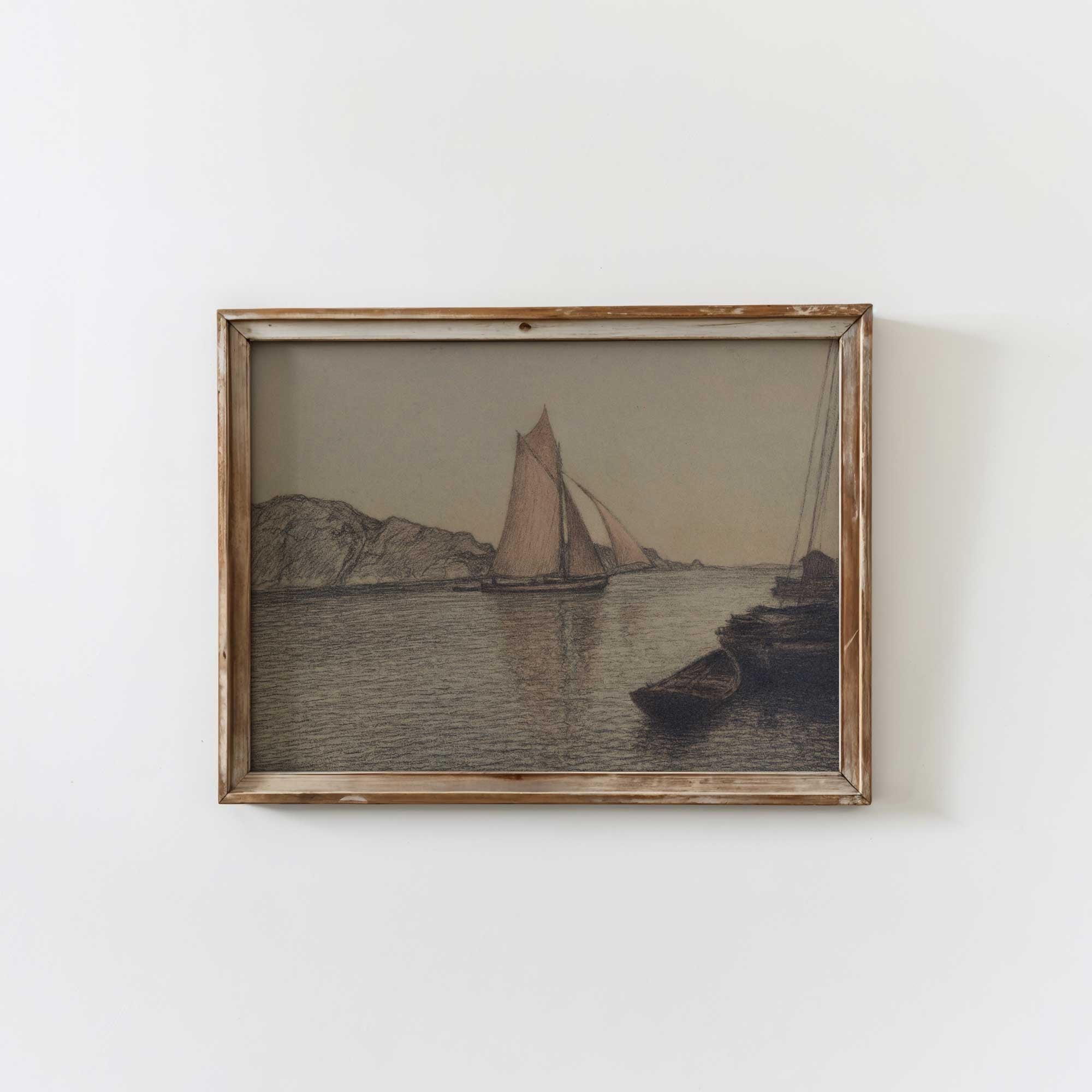 Framed artwork of a sailboat on water with mountains, on a white wall.