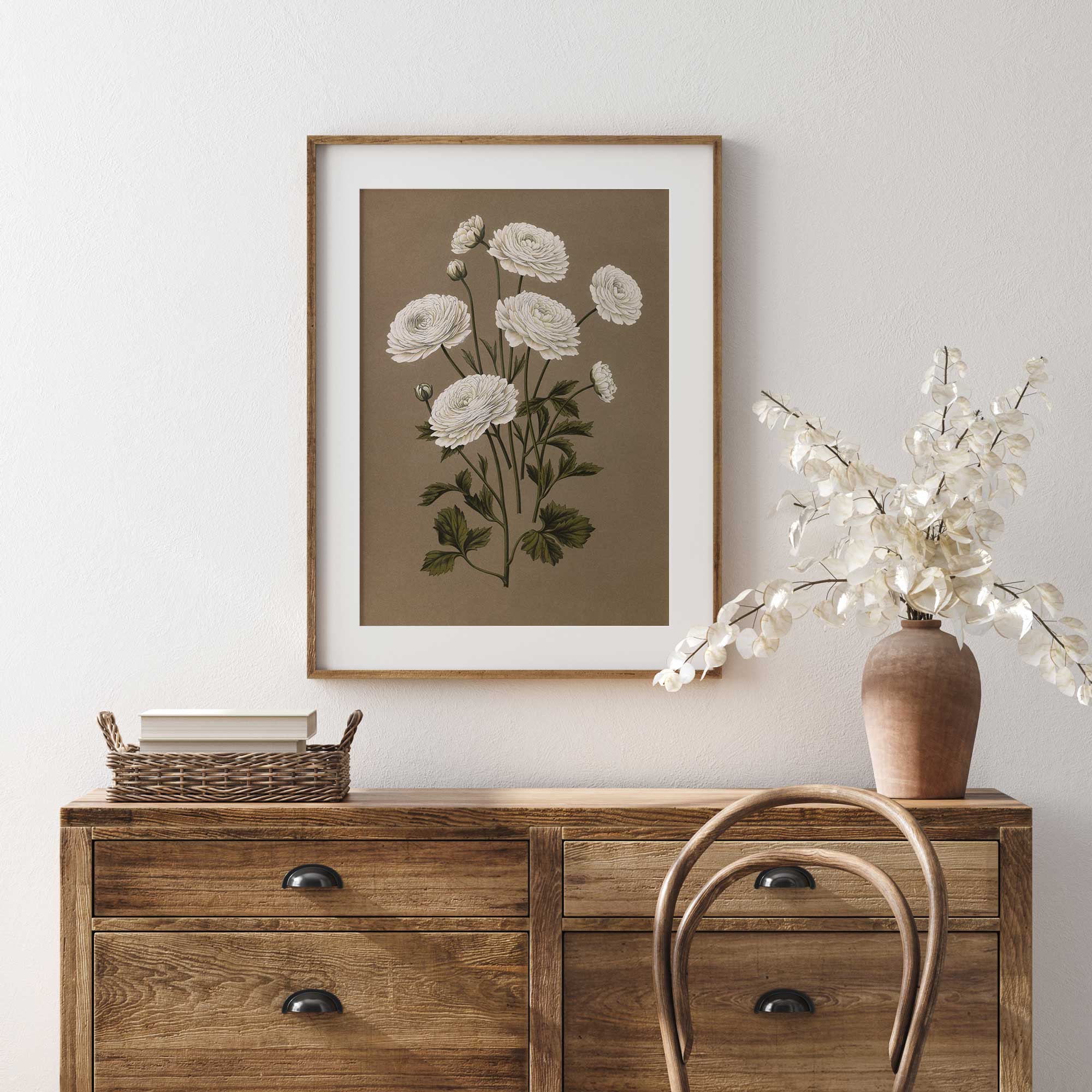 Framed floral print on a wall above a wooden dresser with decorative items.