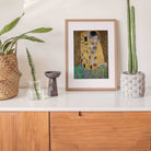 Gustav Klimt – The Kiss, vintage golden fine art print displayed on cabinet in wooden frame