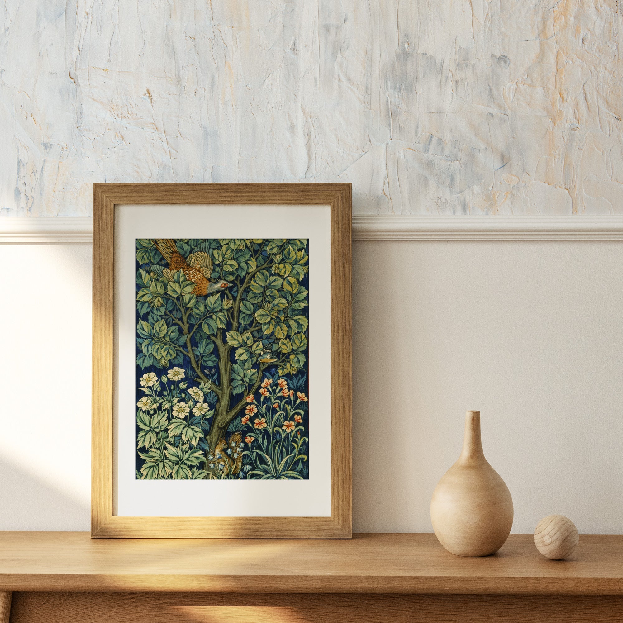 William Morris Pheasant in the Garden Tapestry  Print, Botanical Textile Wall Art in a wooden frame displayed on a cabinet.